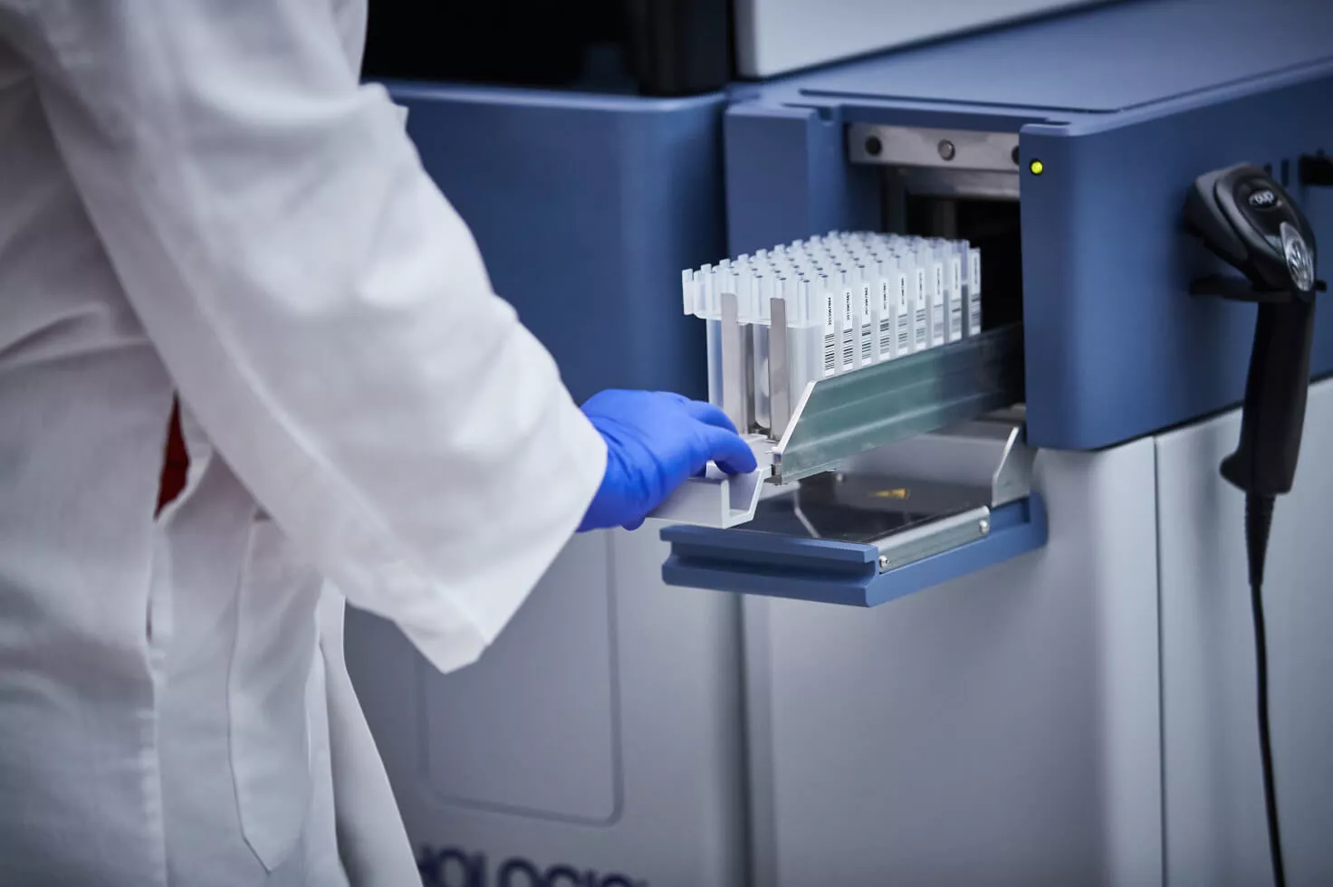 Technicien de laboratoire introduisant un plateau de flacons dans un dispositif médical